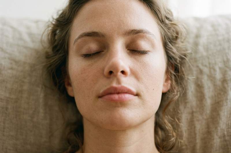 Close-up of a woman's face with her eyes closed and features relaxed in a moment of deep release and burnout recovery